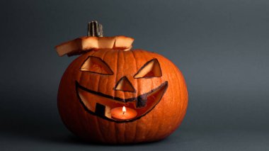 Cadılar Bayramı balkabağı ya da gri arka planda parlayan gözleri olan balkabağı feneri. Cadılar bayramı için Jack-o-fener masada duruyor. Cadılar Bayramını kutlamaya hazırlanıyorum. Gri arkaplanda telif alanı olan Cadılar Bayramı balkabağı..