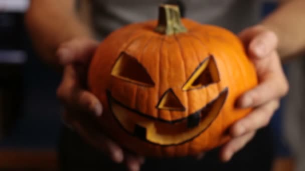 De jonge meester maakte een jack-o-lantaarn voor het Halloween feest.Een jonge man, houdt een Halloween pompoen of jack-o-lantaarn . — Stockvideo