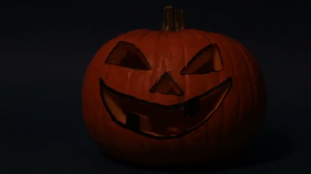 Jack-o-lucerna pro halloweenskou párty stojí na stole na tmavém pozadí. Halloween dýně nebo jack-o-lucerna se zářícíma očima na modrém pozadí. — Stock video