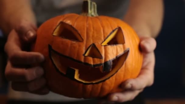 The young master made a jack-o-lantern for the Halloween party.A young man, holds out a halloween pumpkin or jack-o-lantern . — Stock Video