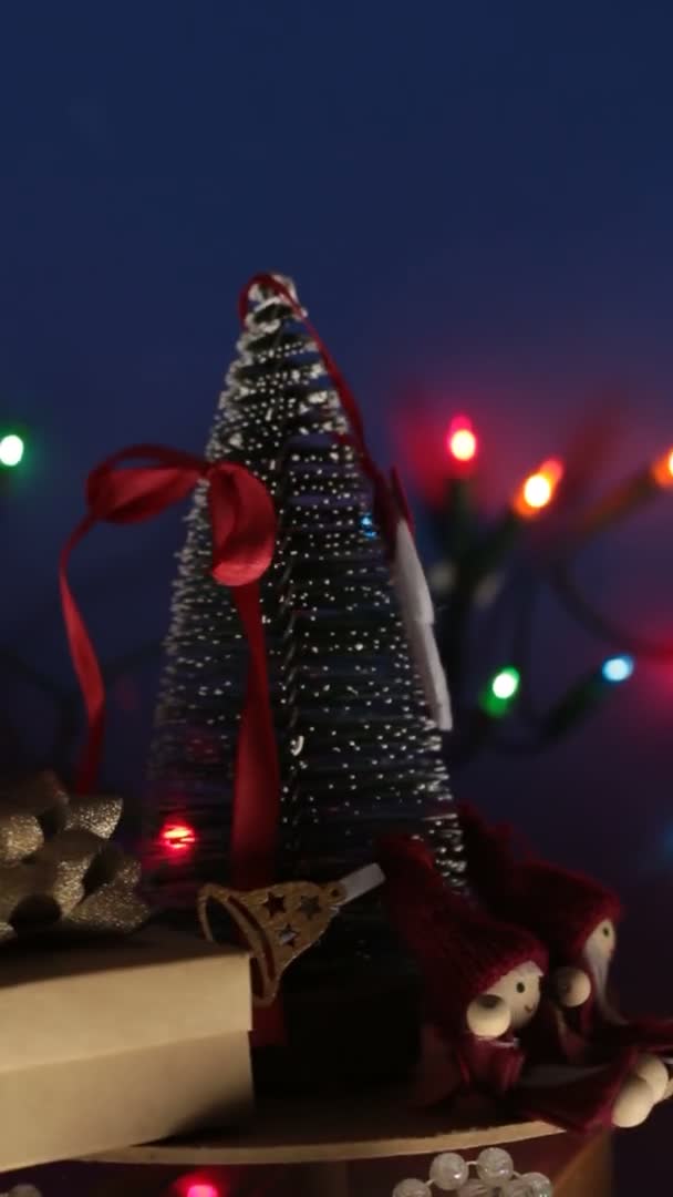 Vertical video New Years festive tree with gifts on the background of a bright garland.Decoration for the new year.Christmas carousel with a Christmas tree and bright gifts. — Stock Video