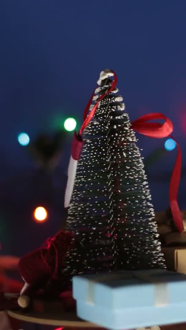 具有明亮花园背景的带有礼物的垂直视频新年圣诞树。新年装饰。圣诞树和明亮的礼物装饰圣诞旋转木马. — 图库视频影像