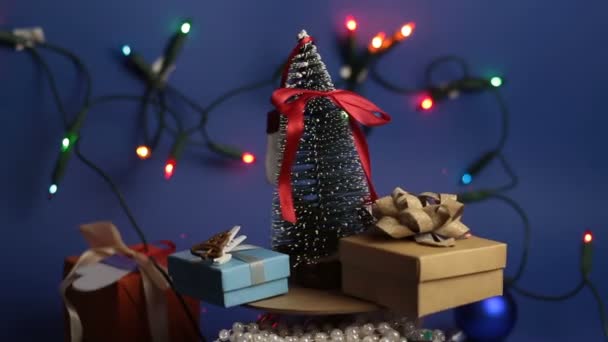 Carrossel de Natal com uma árvore de Natal e presentes brilhantes. Árvore festiva de Ano Novo com presentes no fundo de uma grinalda brilhante. — Vídeo de Stock