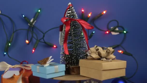 Karácsonyi körhinta karácsonyfával és fényes ajándékokkal. Szilveszter ünnepi fa ajándékokkal a háttérben egy fényes koszorú.Díszítés az új évre. — Stock videók