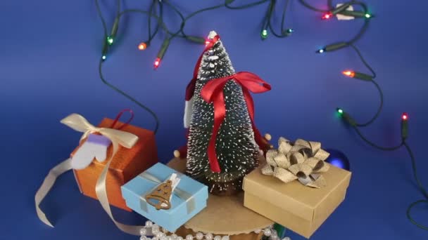 Świąteczna karuzela z choinką i jasnymi prezentami. Noworoczne drzewo świąteczne z prezentami na tle jasnej girlandy.Dekoracja na nowy rok. — Wideo stockowe