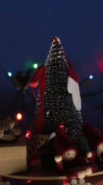 Aydınlık bir çelenk arka planında hediyeler olan dikey Yeni Yıl şenlik ağacı. Yeni yıl için dekorasyon. Noel ağacı ve parlak hediyeli Noel atlıkarınca..