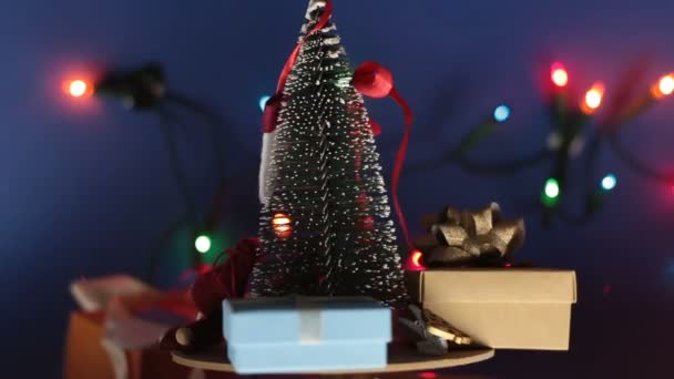 Weihnachtskarussell mit Weihnachtsbaum und bunten Geschenken. Neujahrsbaum mit Geschenken auf dem Hintergrund eines hellen Kranzes. Dekoration für das neue Jahr. — Stockvideo