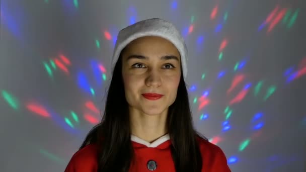 Portrait en gros plan d'une jeune femme heureuse, elle est d'humeur festive en train d'essayer un costume de Père Noël, se préparant pour Noël. Jeune femme attrayante dans un costume de nouvelle année sourit largement contre la — Video