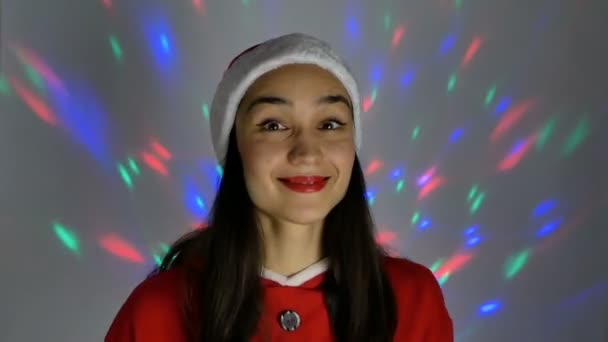 Yeni yıl kostümlü çekici genç bir kadın çok renkli bir çelengin arka planına gülümsüyor.. — Stok video