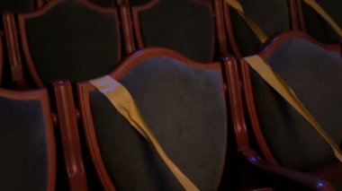  Hijyenik standartlara uymak için sarı bantla kaplı sandalyeleri olan boş bir sinema salonu. Tiyatroda ya da sinema salonunda boş sandalyeler. Sinema salonundaki koltuklar sosyal mesafeyi korumak için bantla kaplıdır. Salgın covid-19. Kimse yok..