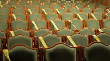  Hijyenik standartlara uymak için sarı bantla kaplı sandalyeleri olan boş bir sinema salonu. Tiyatroda ya da sinema salonunda boş sandalyeler. Sinema salonundaki koltuklar sosyal mesafeyi korumak için bantla kaplıdır. Salgın covid-19. Kimse yok..