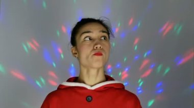 Noel Baba gibi giyinmiş güzel genç bir kadın gülümsüyor ve elinde küçük bir Noel ağacı tutuyor. Yeni yıl tatili.