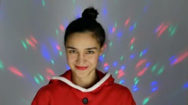 Noel Baba gibi giyinmiş güzel genç bir kadın gülümsüyor ve elinde küçük bir Noel ağacı tutuyor. Yeni yıl tatili.