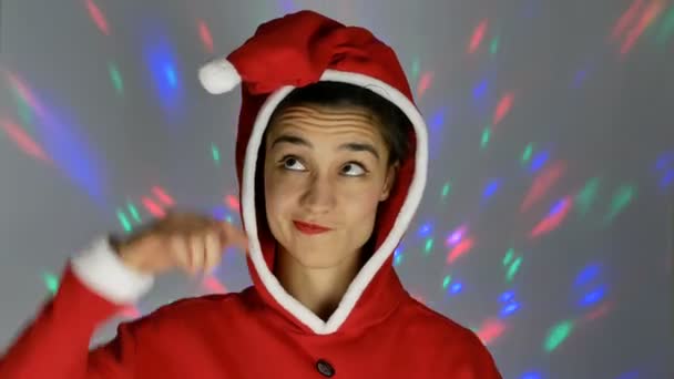 Eine hübsche junge Frau im Weihnachtsmannkostüm lächelt und hält einen kleinen Weihnachtsbaum in den Händen. Neujahrsferien. — Stockvideo