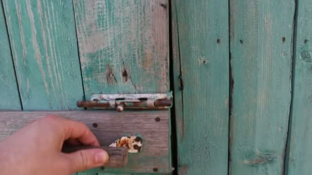 Main masculine ouvre la serrure d'une vieille porte.Gros plan d'une main masculine ouvre une vieille porte avec de la peinture pelée. — Video