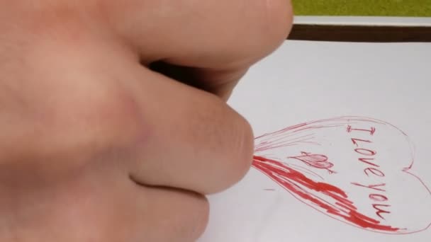 Příprava přání na Valentýna. Mladý muž nakreslí valentýnku pro svou přítelkyni. — Stock video