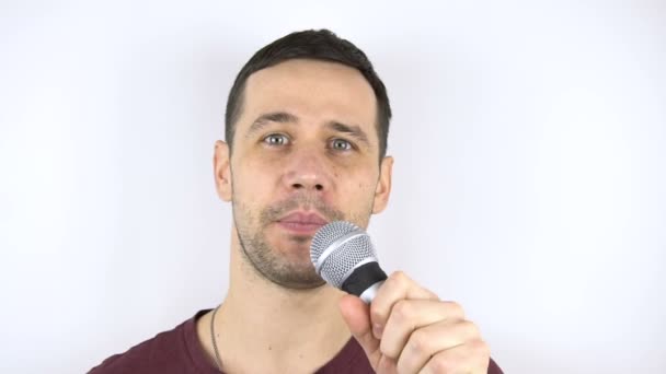 Junger netter Kerl singt in Zeitlupe ein Lied in ein Mikrofon. Junger fröhlicher Stand-up-Comedian spricht vor Publikum. Porträt auf weißem Hintergrund. — Stockvideo