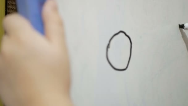 Gros plan d'une petite main de fille, elle dessine avec un flamaster noir sur un tableau blanc. Petite fille attirante dessine avec un marqueur noir sur un tableau blanc. — Video