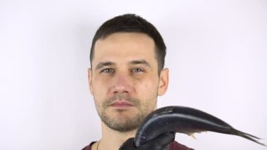 Genç yakışıklı adamın yüzüne taze balık çarpıyor..