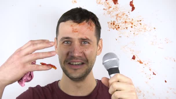 A young attractive stand-up comedian gets shot with tomatoes for poor performance. In slow motion, a tomato smashes against the face of a young stand-up comedian during his speech. — Stock Video