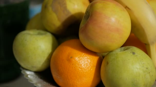 Frische saftige Früchte liegen auf einem Teller. Äpfel, Bananen und Orangen auf dem Teller. — Stockvideo