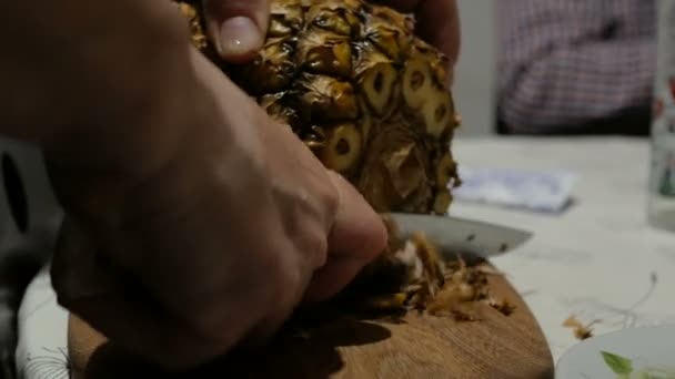 Kvinna kock skalar mogen saftig ananas från skalet.Närbild kvinna kock skär saftig mogen ananas i köket. — Stockvideo