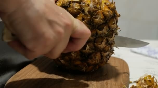 Kvinna kock skalar mogen saftig ananas från skalet. — Stockvideo