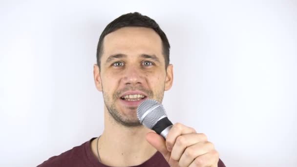 Young cute guy sings a song into a microphone in slow motion.Young happy stand-up comedian speaks in front of an audience. — Stock Video