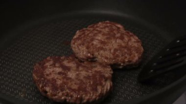 Şef kızartma tavasına köfte koyar. Sulu sığır pirzolası tavada kızarır..
