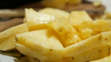 Genç bir adamın elleri, bir tabaktan sulu bir ananas dilimi alır..