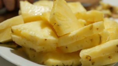 Genç bir adamın ellerine yakın plan bir tabaktan sulu bir ananas dilimi alır. Genç bir adam kendine tatlı, sulu ananas ikram eder..