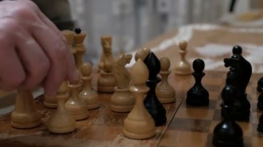 Yaşlı bir adam ve genç bir kadın satranç tahtasına satranç taşları yerleştiriyorlar, oynamaya hazırlanıyorlar. Satranç oynayan bir adamla genç bir kadının yakın çekimi..