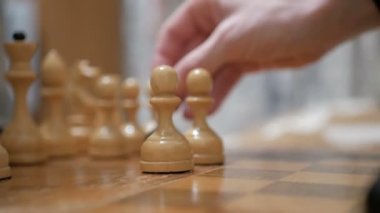 Yaşlı bir adam ve genç bir kadın satranç tahtasına satranç taşları yerleştiriyorlar, oynamaya hazırlanıyorlar. Satranç oynayan bir adamla genç bir kadının yakın çekimi..