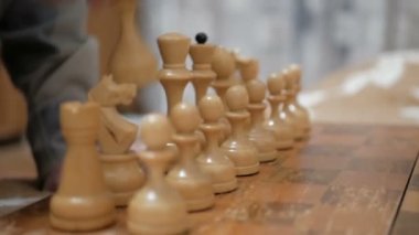 Satranç oynayan bir adam ve genç bir kadının yakın plan çekimleri. Yaşlı bir adam ve genç bir kadın satranç tahtasının üzerinde satranç taşları düzenliyor, oynamaya hazırlanıyorlar..