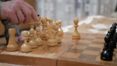 Satranç oynayan bir adam ve genç bir kadının yakın plan çekimleri. Yaşlı bir adam ve genç bir kadın satranç tahtasının üzerinde satranç taşları düzenliyor, oynamaya hazırlanıyorlar..