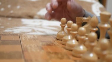 Satranç oynayan bir adam ve genç bir kadının yakın plan çekimleri. Yaşlı bir adam ve genç bir kadın satranç tahtasının üzerinde satranç taşları düzenliyor, oynamaya hazırlanıyorlar..