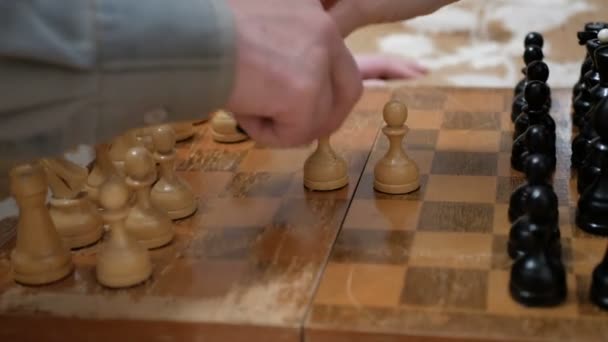 An elderly man and a young woman are arranging chess pieces on a chessboard, getting ready to play.Close-up of the hand of a man and a young woman playing chess. — Stock Video