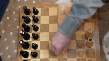 Yaşlı bir adam ve genç bir kadın satranç tahtasına satranç taşları yerleştiriyorlar, oynamaya hazırlanıyorlar. Satranç oynayan bir adamla genç bir kadının yakın çekimi..