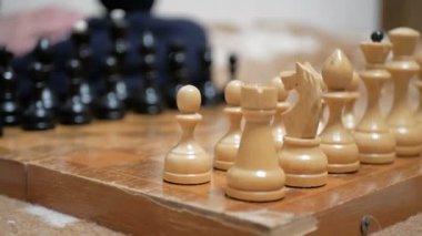 Satranç oynayan bir adam ve genç bir kadının yakın plan çekimleri. Yaşlı bir adam ve genç bir kadın satranç tahtasının üzerinde satranç taşları düzenliyor, oynamaya hazırlanıyorlar..