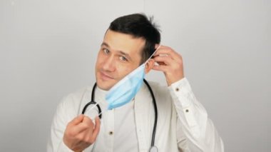 Genç yakışıklı doktor hastaları muayene etmek için tıbbi maske takıyor..