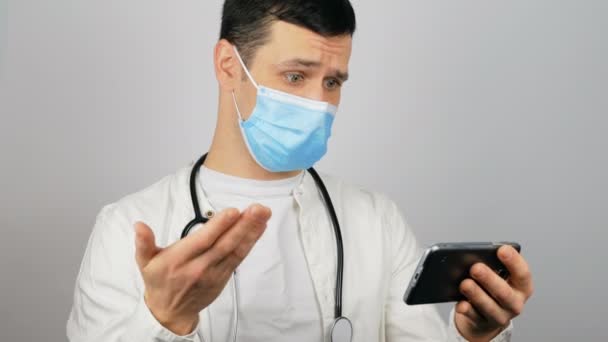 A handsome young doctor talks to his patient via video call and prescribes treatment. — Stock Video