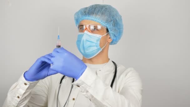 Le mani dei medici riempiono la siringa di vaccino, preparandosi per l'iniezione al paziente.Un giovane medico bello si prepara per la vaccinazione, prepara una siringa con un vaccino prima di un — Video Stock