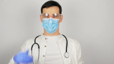 Güvenlik gözlüklü ve tıbbi koruyucu maskeli genç ve yakışıklı bir doktor araştırmanın sonucuna seviniyor..