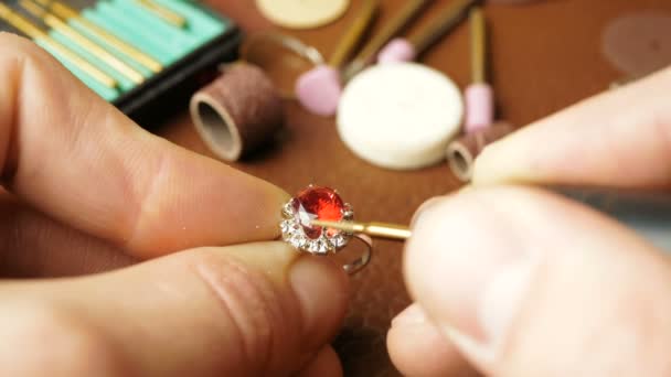 A professional engraver creates a piece of jewelry. Jewelry processing, gemstone polishing by a professional jeweler.A jeweler is cutting a precious stone on a gold ring. A professional jeweler — Stock Video