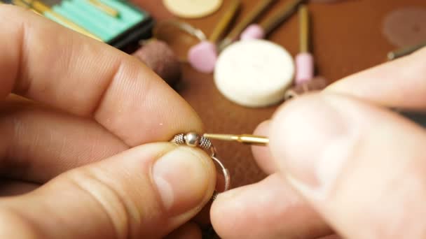 Ein professioneller Juwelier poliert Silberohrringe mit einem speziellen Werkzeug. Ein professioneller Graveur stellt ein Schmuckstück her. — Stockvideo
