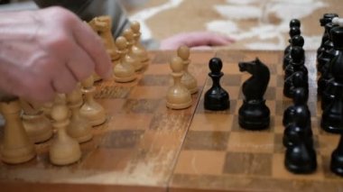 Satranç oynayan bir adam ve genç bir kadının yakın plan çekimleri. Yaşlı bir adam ve genç bir kadın satranç tahtasının üzerinde satranç taşları düzenliyor, oynamaya hazırlanıyorlar..