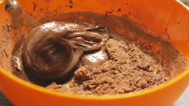 De chef mengt de chocoladecrème voor de taart met een mixer. Close-up van een chef-kok die met een blender een chocoladedededeeg roert om een brownie te maken. — Stockvideo