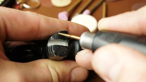 Ein professioneller Juwelier graviert in eine Steinfigur ein Schmuckstück. Ein professioneller Graveur erstellt ein Schmuckstück, indem er mit einem speziellen Fräser Rillen anfertigt. — Stockvideo