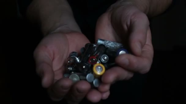 Um homem tem um punhado de baterias alcalinas usadas. Close-up de um homem mão segurando baterias alcalinas usadas. Conceito de protecção ambiental — Vídeo de Stock