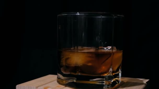 Un barman profesionist toarnă whisky într-un pahar cu gheață. Închiderea unui pahar fațetat cu gheață în care barmanul toarnă whisky în vârstă . — Videoclip de stoc